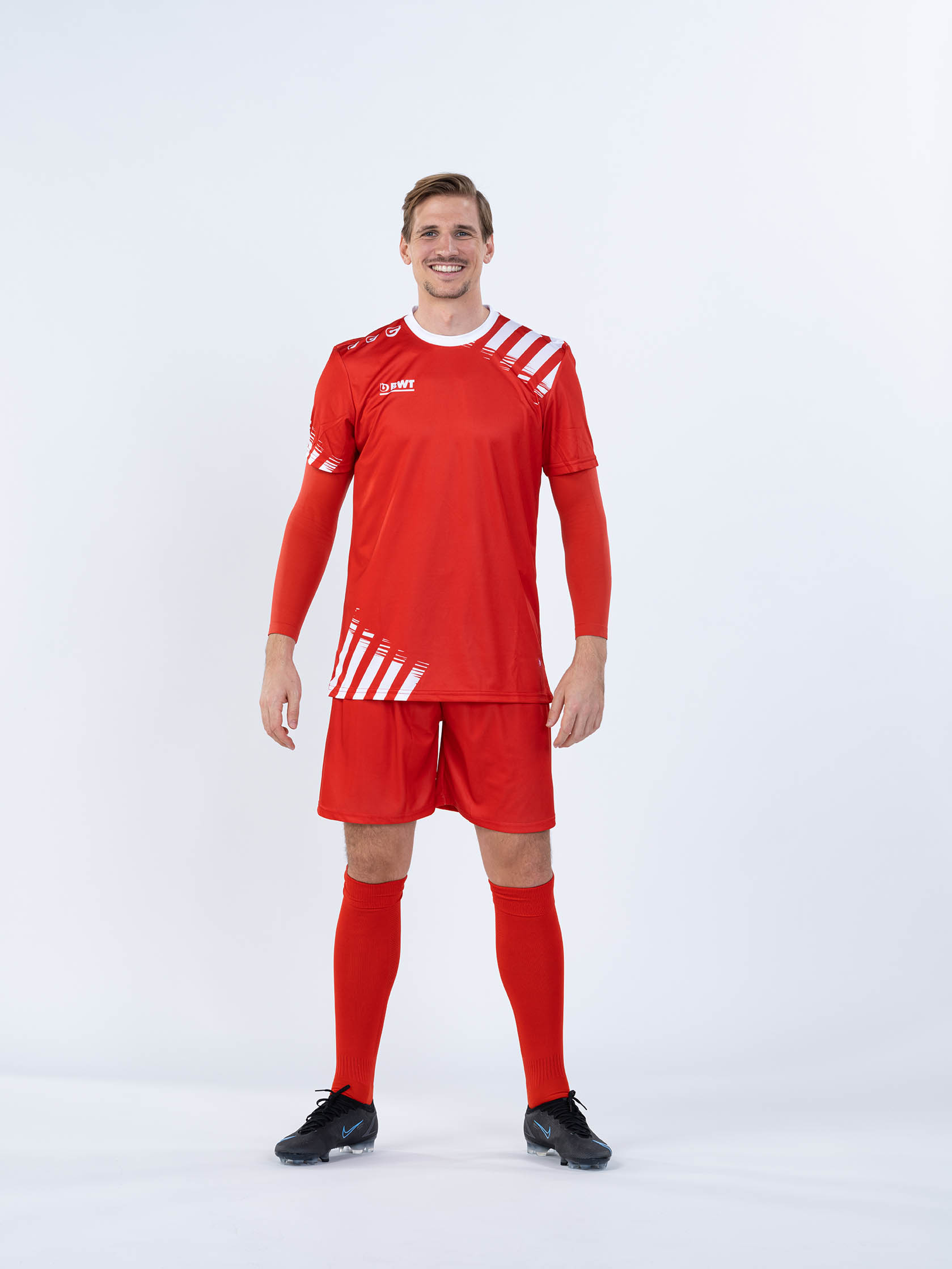 Herr trägt BWT One Fußballtrikot mit Shirt, Hose und Stutzen in rot